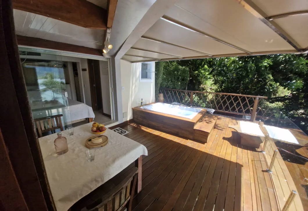 Deck coberto do Chalé Jabuticabeira com mesa e hidromassagem privativa