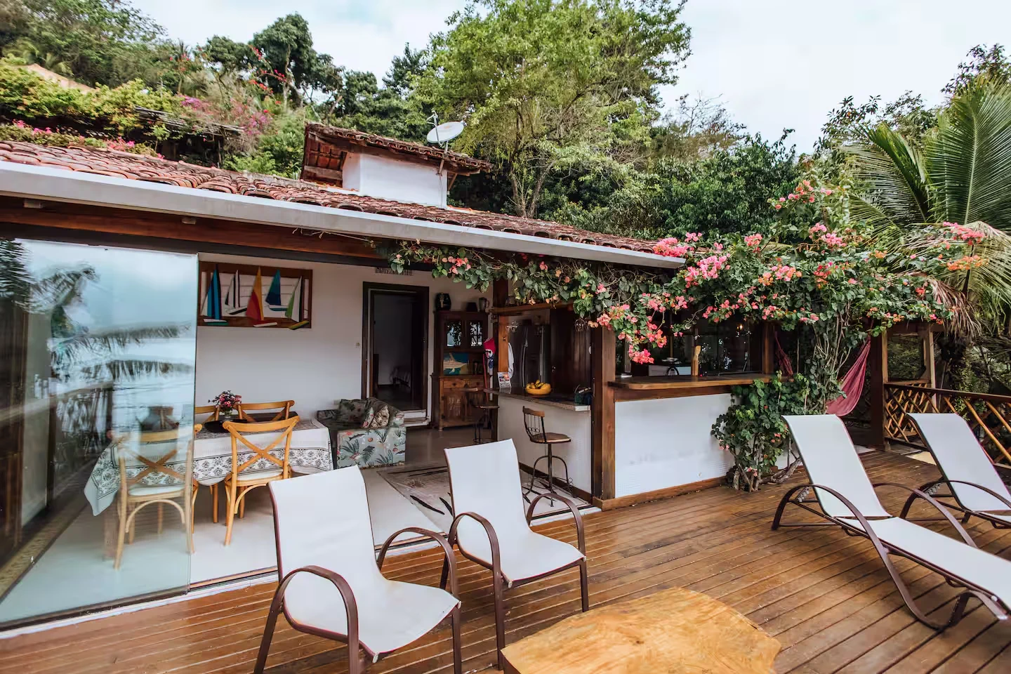 Deck de madeira da Casa dos Tucanos cercado por flores e vegetação