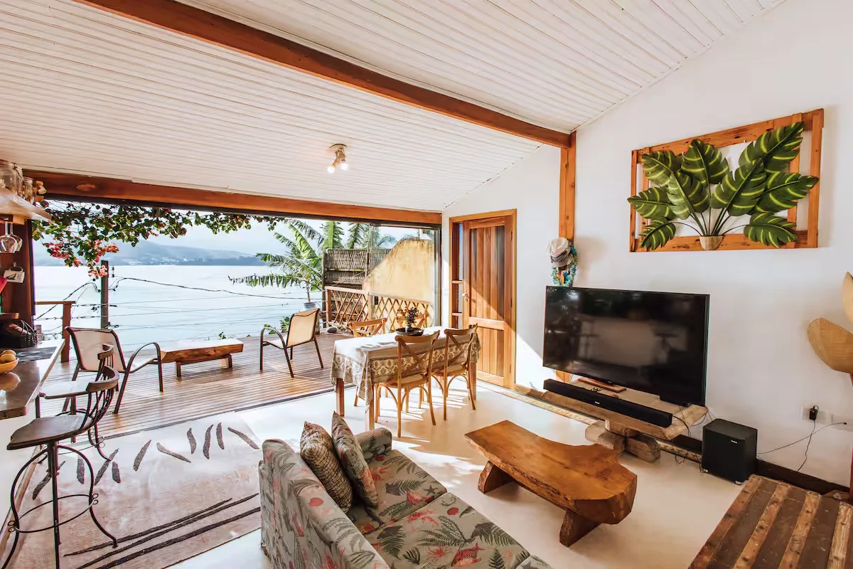 Sala ampla e integrada da Casa dos Tucanos com vista para o mar